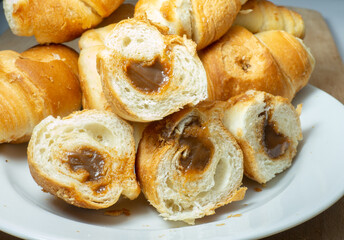 Many small croissants on a white background. Croissants with boiled condensed milk. Confectionery in the kitchen. Fluffy soft pastries.