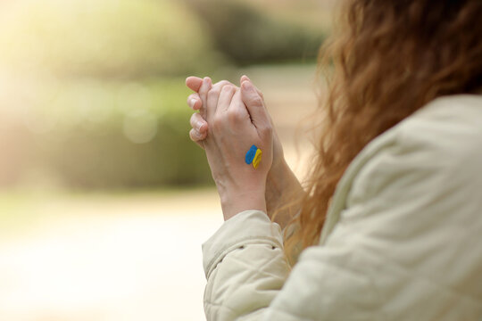 Stop War. Peace in Ukraine. woman hands with picture of flag of ukraine, hands folded in prayer. Antiwar support concept.