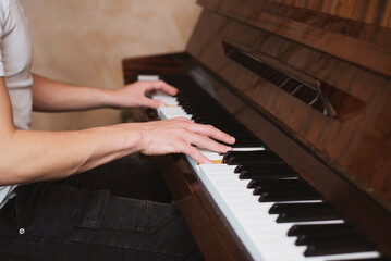 On the keys of a classical piano the hands of a teenage boy, the boy learns to play the piano at...