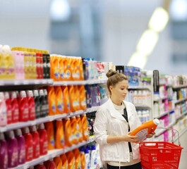 Woman shopping in supermarket reading product information.woman choosing laundry detergent in supermarket