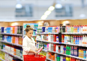 Woman shopping in supermarket reading product information.woman choosing laundry detergent in...