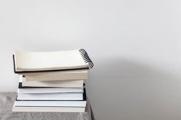 There is a stack of books on a beige table against a white wall. Scandinavian style. Minimalism....