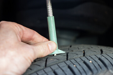 Checking tread depth on a tire with a tire gauge