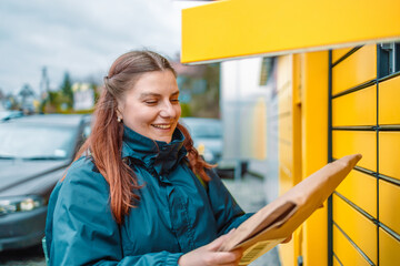 Caucasian woman send or receive parcel with yellow self service post terminal machine. 
