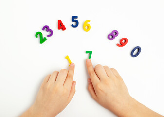 Children's hands move numbers on a white table. Learning colors and to count from zero to ten