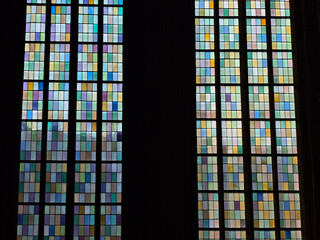 Beautiful view of the colorful glass window of a church with dark frames and sunlight shining through.