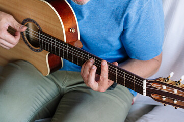 Fototapeta na wymiar Adult man studying guitar online with tablet at home.