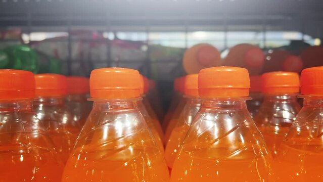 Orange lemonade in plastic bottles is on the shelves of grocery store. Closeup