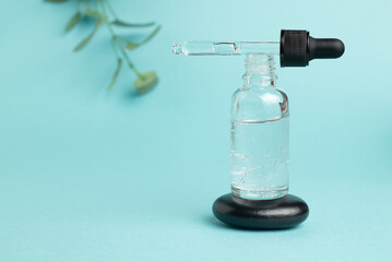 Cosmetic mean for facial care. Pipette bottle on stone filled with essential oil, essence, serum...