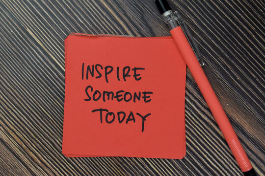 Inspire Someone Today write on sticky notes isolated on Wooden Table.