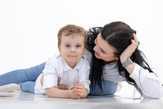Happy smiling woman and boy lying on floor, white background. Hugging, talking caring parenthood. Autism spectrum. Close
