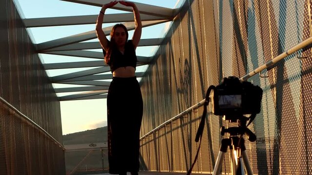 portrait of a young blonde Caucasian woman filming dance classes with her camera outdoors. joyful rhythm