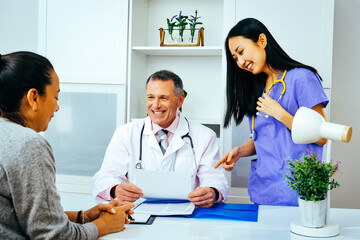 Fototapeta premium happy doctor and nurse talking to adult female patient in hospital consultation healthcare industry