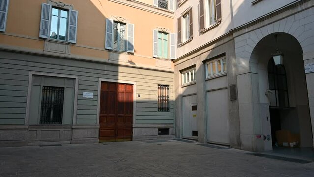 Milan, Italy, March 2022. Tilt footage of the piazzetta Enrico Cuccia, a famous Milanese banker. The warm spring light illuminates the historic buildings that overlook the square.