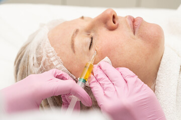 Cosmetologist makes prp therapy against wrinkles around the eyes and skin aging on the face of an...