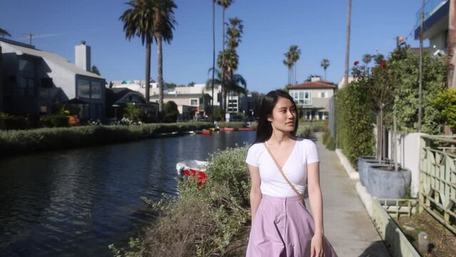 A young Asian woman walking the canal of Venice Beach, a famous tourist destination in Los Angeles