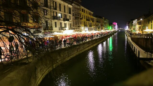 Milan, Italy, March 2022. Footage of the Naviglio Grande at night: the restaurants are open and the lights illuminate the street, a great passage of people for aperitif and dinner time.