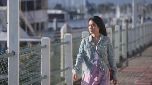 A young Asian woman walking through Marina del Rey, a famous tourist destination in Los Angeles
