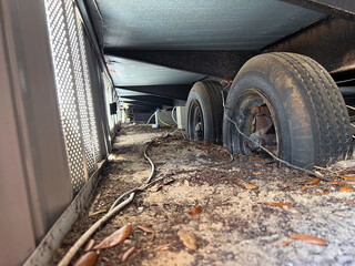 Fototapeta na wymiar Crawlspace underneath manufactured home with old destroyed wheels on trailer