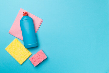 Bottle with dishwashing detergent and sponges on color background, top view