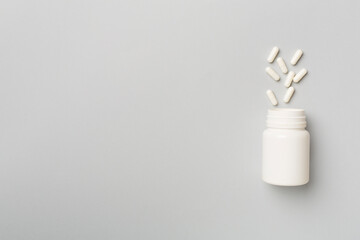 White bottle with pills on color background