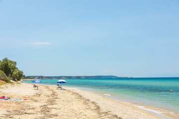Fototapeta na wymiar Beautiful seascape view. People on sand beach on turquoise water and blue sky background. Greece.