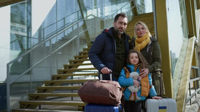 Ukrainian refugee family with luggage at railway station hugging and saying goodbye, Ukrainian war concept.
