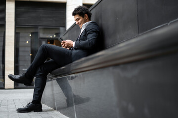 A male business manager in a formal suit uses the phone and goes to work in the office