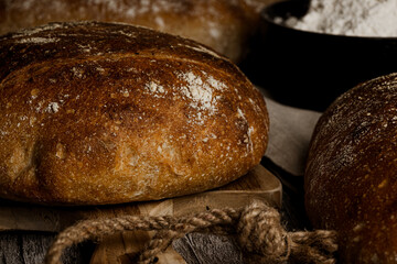 close-up photo of several artisan breads cut from wholemeal flour with a jar of flour on a rustic wooden table