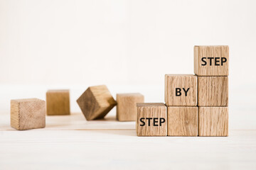 The word step by step on wooden cubes. Achievement or progress in business career.