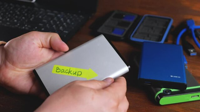 Stick sticker with BACKUP text on external hard drive. 2.5-inch HDD form factor. Hard disk drive for data storage. Copy of computer data taken and stored elsewhere. Restore original after data loss