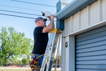 Technician installing a security camera at a storage facility.