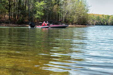 Fototapeta na wymiar Bass boat with two fisherman heading out to a new fishing location on Tim’s Ford Lake on a sunny day.
