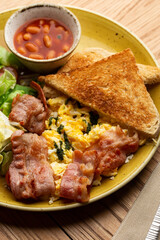 Poached eggs with vegetable, ham, tomatoes, red beans and sourdough toast isolated on wood background. Homemade food. Tasty breakfast.