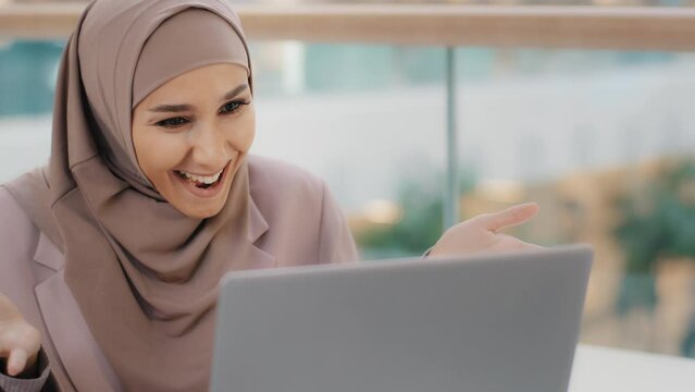 Happy arab woman looking at laptop screen checking email smiling reading good news rejoicing in achievement getting new job career growth feeling motivated victory good price offer winning lottery