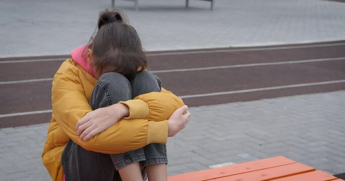 Teen with problems on street. An upset teenage girl with life problems sits on the playground.