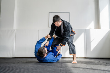 Two brazilian jiu jitsu BJJ athletes training at the academy martial arts ground fighting sparring...