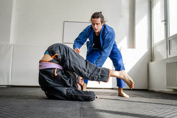 Two brazilian jiu jitsu BJJ athletes training at the academy martial arts ground fighting sparring...