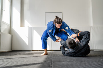 Two brazilian jiu jitsu BJJ athletes training at the academy martial arts ground fighting sparring...