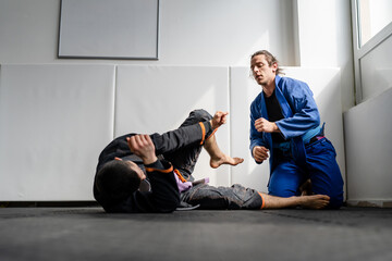 Two brazilian jiu jitsu BJJ athletes training at the academy martial arts ground fighting sparring...