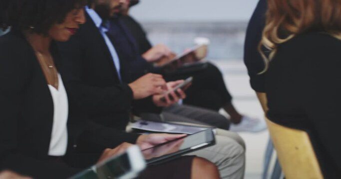 There's always opportunity to learn. Group of diverse businesspeople sitting in conference room listening to training seminar taking notes using their notepads and phones during workshop presentation