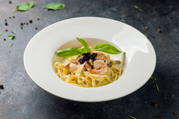 Pasta fettuccine with shrimps and creamy sauce  on dark stone table