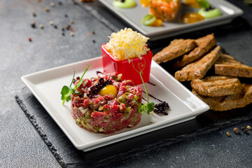Tartare from beef on white plate with egg and croutons