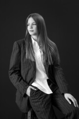 Studio portrait of fashionable girl in white button down shirt and striped oversized suit.