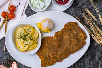 Vienna schnitzel from veal with potatoes and lemon on white plate top view