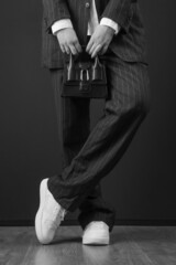 Fashionable trendy woman holding top handle mini black bag. Studio shot on black background.