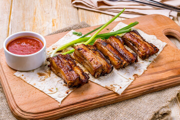 skewers of pork ribs with tomato sauce and green onion on the board