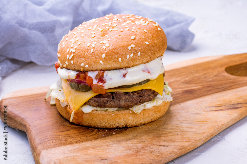 Wall mural Burger with meat patty, cheese and vegetables macro close up