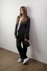 Studio portrait of fashionable girl in white button down shirt and striped oversized suit.