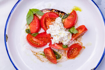 Salad with buratta cheese and tomatoes on bowl on grey table top view